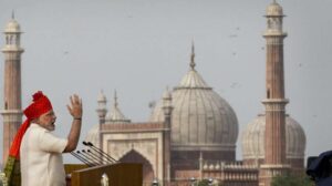 प्रधानमंत्री नरेंद्र मोदी का भाषण देते हुए प्रतीकात्मक दृश्य, बैकग्राउंड में संसद भवन का माहौल